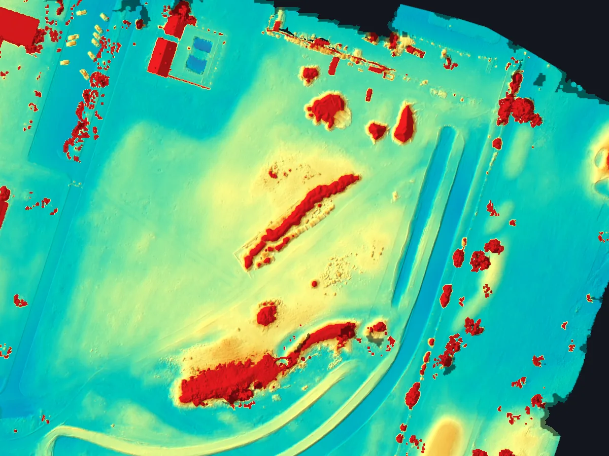 Color elevation model of the Costa Mesa site: low ground in blue and green, stockpiles and berms in yellow and red, with shaded relief.